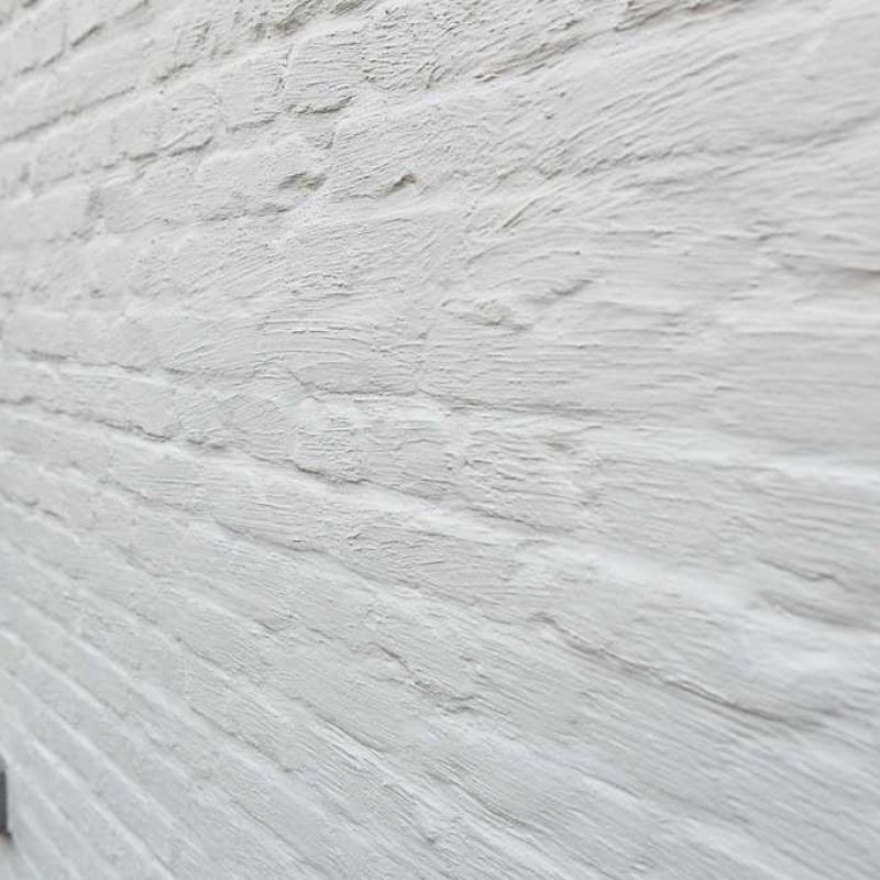 kaleii_11zon Witte bakstenen muur met raamkozijn.